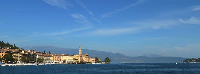 Trip Oberösterreich beliebte Urlaubsziele am Gardasee -  Mit einer Fläche von 370 km² ist der Gardasee der größte See Italiens. Es liegt am Fuße der Alpen und erstreckt sich über drei Staaten: Lombardei, Venetien und Trentino. Die maximale Tiefe des Sees beträgt 346 m, er hat eine längliche Form und sein nördliches Ende ist sehr schmal. Dort ist der See von den Bergen der Gruppo di Baldo umgeben. Du trittst aus deinem gemütlichen Hotelzimmer und es begrüßt dich die warme italienische Sonne. Du blickst auf den atemberaubenden Gardasee, der in zahlreichen Blautönen schimmert - von tiefem Dunkelblau bis zu funkelndem Türkis. Majestätische Berge umgeben dich, während die Brise sanft deine Haut streichelt und der Duft von blühenden Zitronenbäumen deine Nase kitzelt. Du schlenderst die malerischen, engen Gassen entlang, vorbei an farbenfrohen, blumengeschmückten Häusern. Vereinzelt unterbricht das fröhliche Lachen der Einheimischen die friedvolle Stille. Du fühlst dich wie in einem Traum, der nicht enden will. Jeder Schritt führt dich zu neuen Entdeckungen und Abenteuern. Du probierst die köstliche italienische Küche mit ihren frischen Zutaten und verführerischen Aromen. Die Sonne geht langsam unter und taucht den Himmel in ein leuchtendes Orange-rot - ein spektakulärer Anblick.